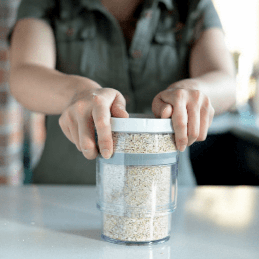 Person using Flexseal vacuum container to seal oats, preserving freshness for snacks and dry foods.